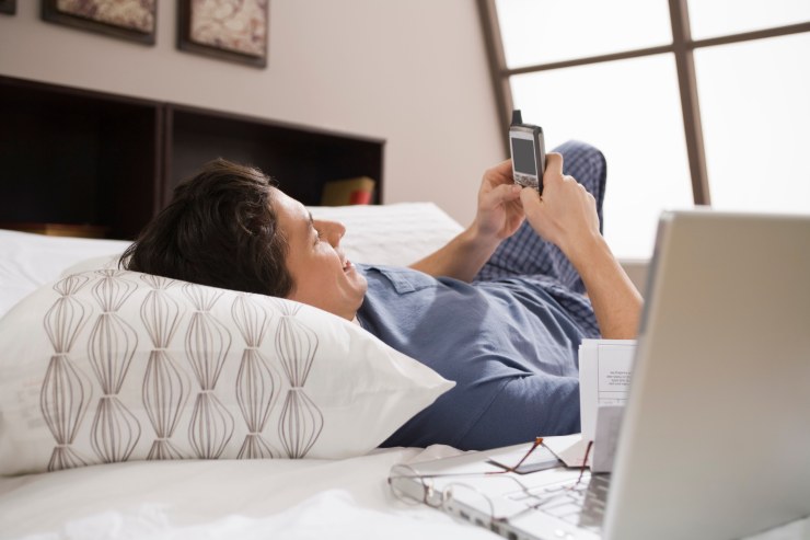uomo a letto con cellulare tra le mani