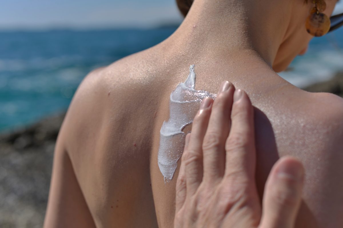 Persona che spalma la crema solare sulla schiena di una donna