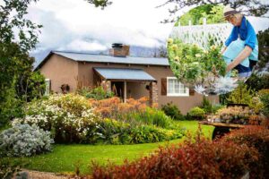 casa con giardino e donna che annaffia