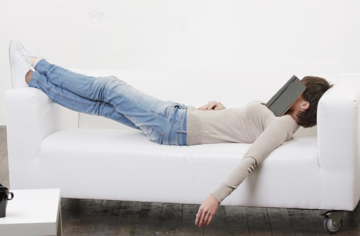 Ragazza che dorme sul divano con il libro in faccia