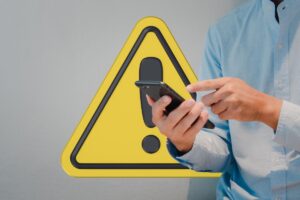 Uomo che guarda il telefono e segnale di allerta sullo sfondo