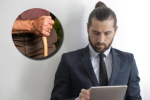 Un ragazzo in giacca e cravatta con un tablet e, in evidenza, la mano di un anziano