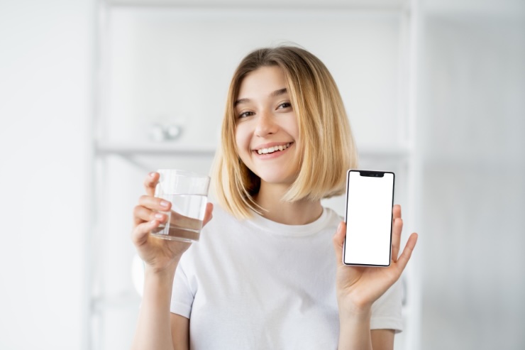 donna con bicchiere di acqua e smartphone