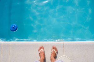 Piedi con infradito a bordo piscina e cloro vicino