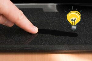 Persona che passa un dito sul piedino della tv pieno di polvere e adesivo lampadina