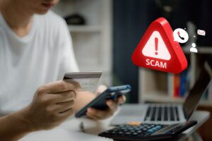 Ragazzo con smartphone e carta di credito in mano che compra su un e-commerce. Logo allerta scam