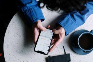 Mani che reggono su un tavolino un telefono collegato a un chat WhatsApp