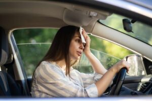 donna che si asciuga sudore in auto
