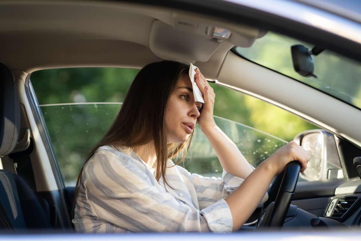 donna che si asciuga sudore in auto