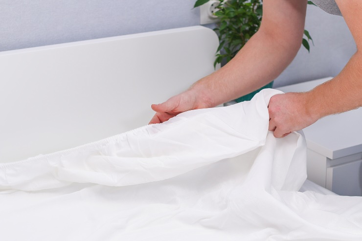 mani che cambiano lenzuola letto