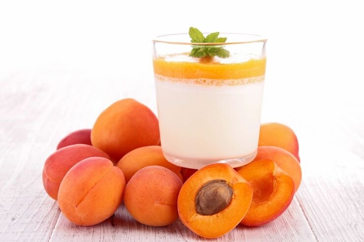 Albicocche e bicchiere con yogurt e albicocche schiacciate e fogliolina menta